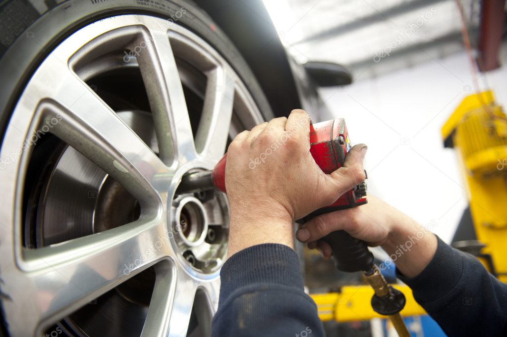 Mechanik wymieniający koło w serwisie opon