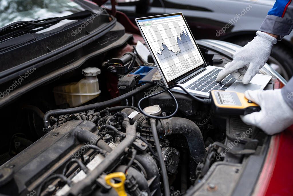 Mechanik podłączający komputer diagnostyczny do auta
