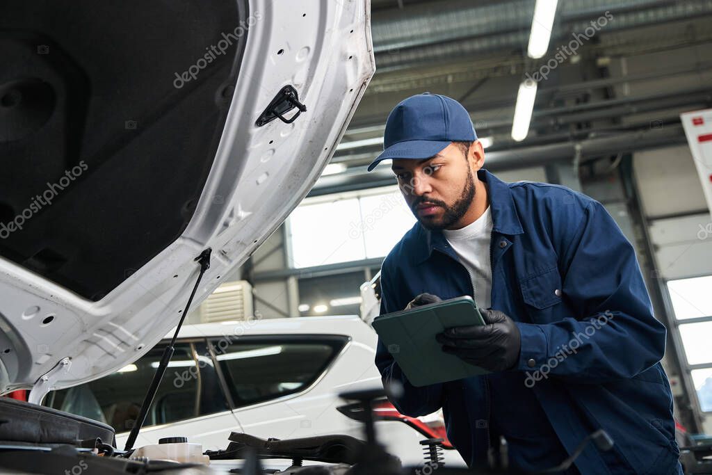 Zespół mechaników pracujących przy samochodzie w warsztacie